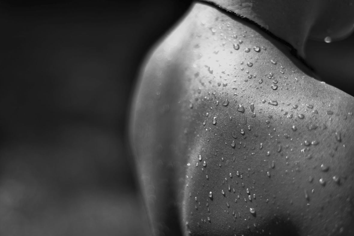 A black and white image of a persons back covered in water droplets