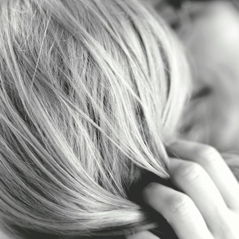 A black and white image of a man running his hand through a ladies blonde hair